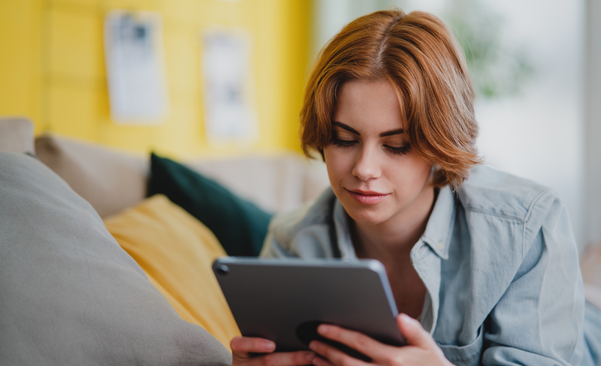 Portrait of young woman using smartphone, lying on sofa at home, social networks concept.